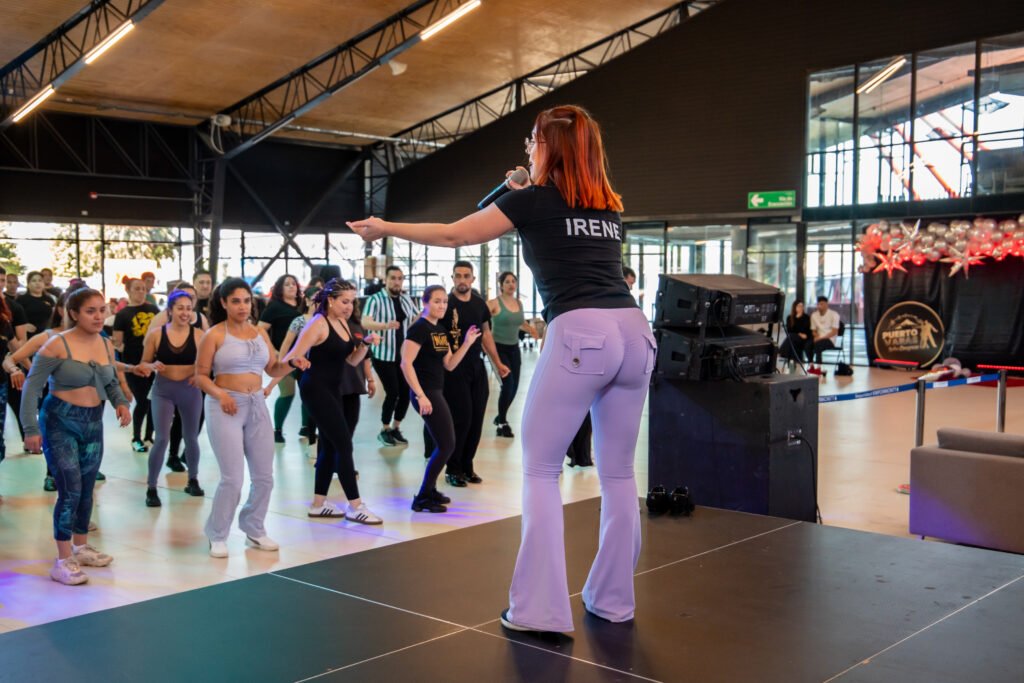 Irene Palomares, de espaldas y con micrófono, dirigiendo el footwork de un grupo grande de alumnas en un taller