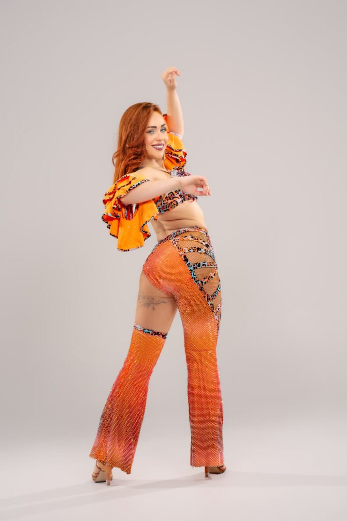 Irene Palomares con el traje naranja de baile, brazos en alto